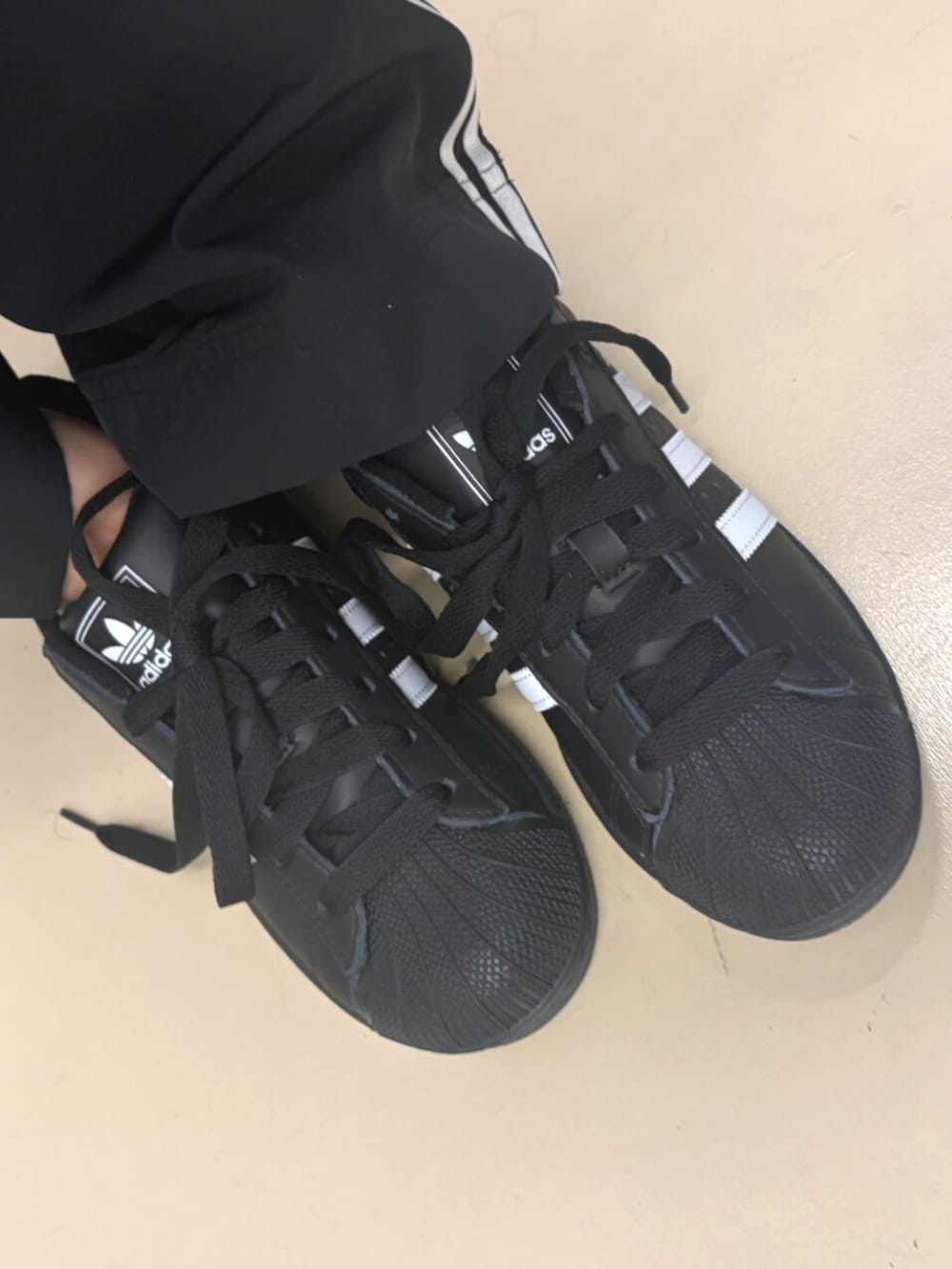 ブラック系のスニーカー、ホワイト系のトップス、ブラック系のジャージを着用したレディースの春コーディネートの2枚目の写真