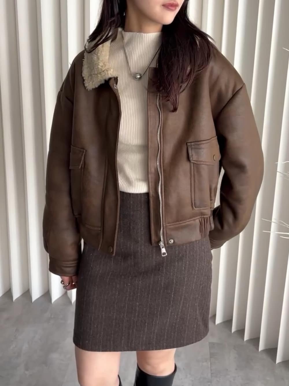 ブラウン系のブルゾン、ブラウン系のスカート、ホワイト系のニット/セーターを着用したレディースの冬コーディネートの2枚目の写真