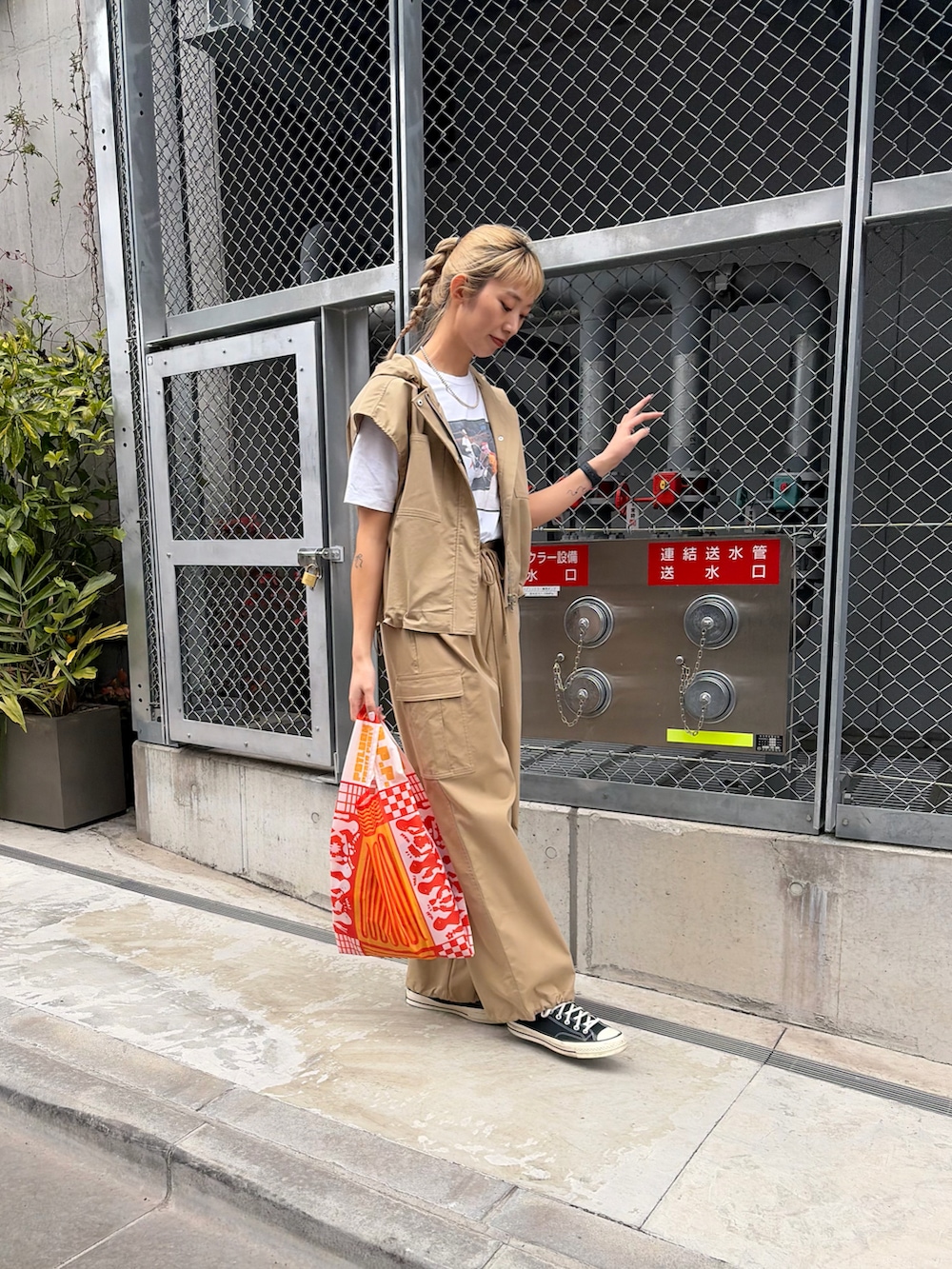 ベージュ系のベスト、ベージュ系のカーゴパンツ、オレンジ系のエコバッグ/サブバッグを着用したレディースの春コーディネートの3枚目の写真