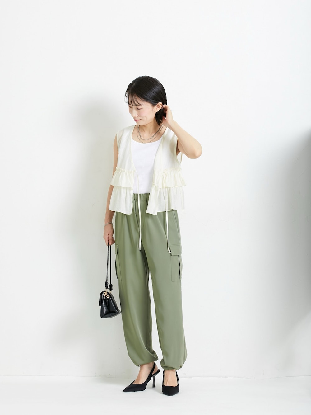 ブルー系のベスト、ホワイト系のキャミソール、グリーン系のカーゴパンツを着用したレディースの春コーディネートの2枚目の写真