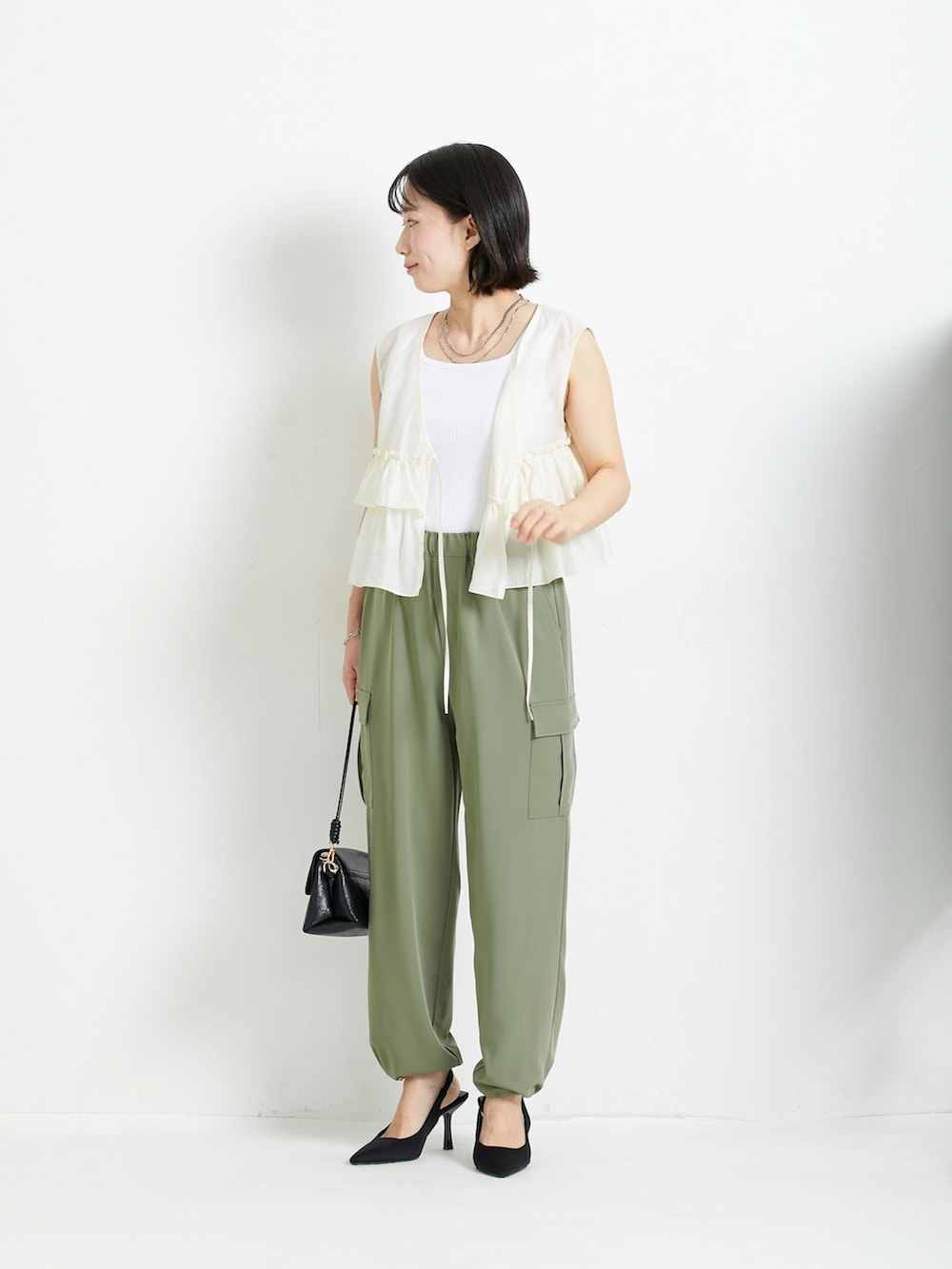 ブルー系のベスト、ホワイト系のキャミソール、グリーン系のカーゴパンツを着用したレディースの春コーディネートの3枚目の写真