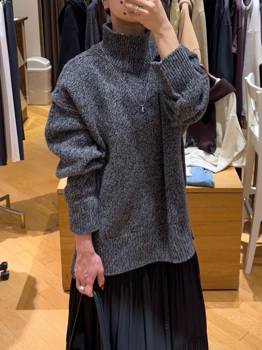 グレー系のニット/セーター、ブラック系のスカート、ブラック系のブーツを着用したレディースの秋コーディネートの8枚目の写真