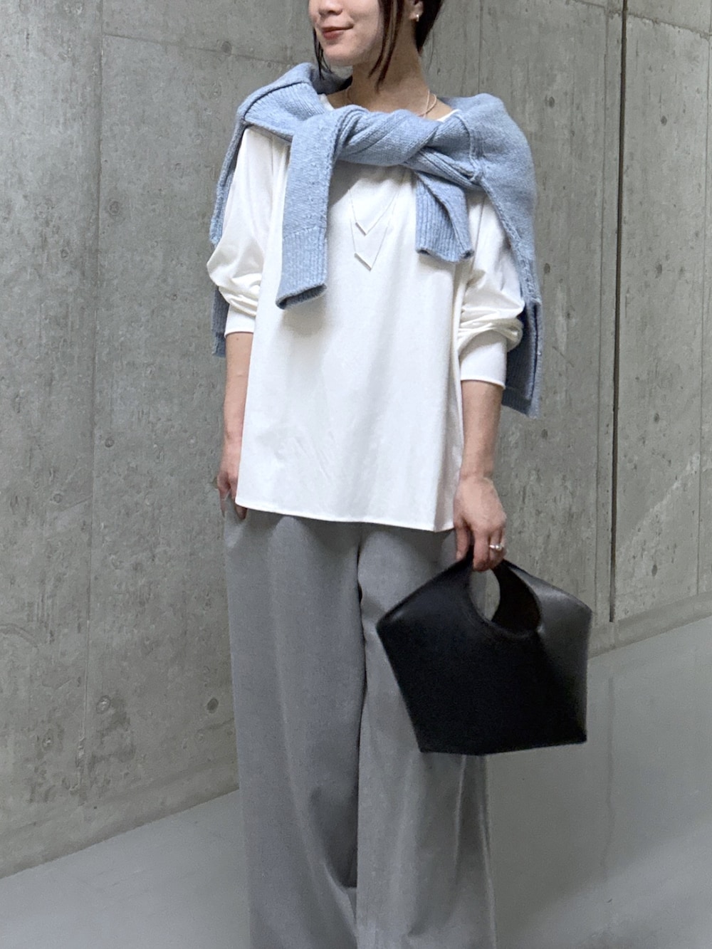 ブルー系のニット/セーター、ホワイト系のTシャツ/カットソー、ブラック系のハンドバッグを着用したレディースの秋コーディネートの4枚目の写真