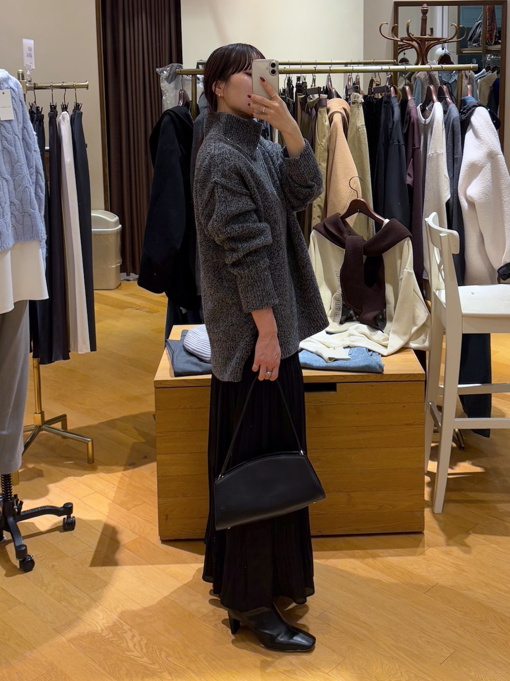 グレー系のニット/セーター、ブラック系のスカート、ブラック系のブーツを着用したレディースの秋コーディネートの2枚目の写真
