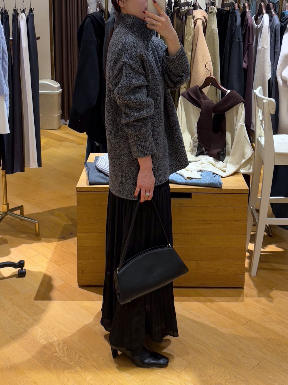 グレー系のニット/セーター、ブラック系のスカート、ブラック系のブーツを着用したレディースの秋コーディネートの7枚目の写真