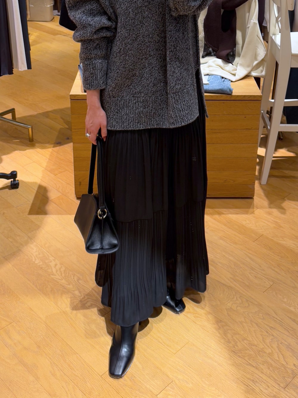 グレー系のニット/セーター、ブラック系のスカート、ブラック系のブーツを着用したレディースの秋コーディネートの6枚目の写真