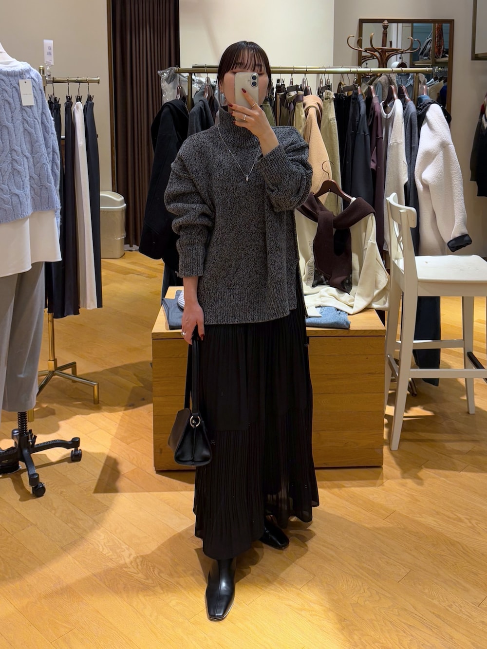 グレー系のニット/セーター、ブラック系のスカート、ブラック系のブーツを着用したレディースの秋コーディネートの5枚目の写真