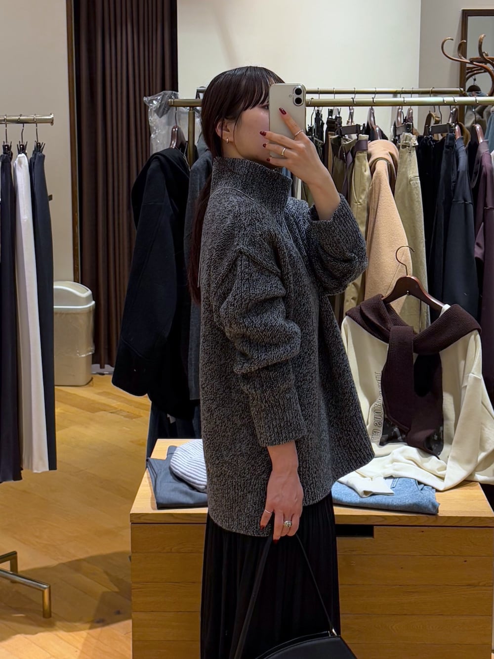 グレー系のニット/セーター、ブラック系のスカート、ブラック系のブーツを着用したレディースの秋コーディネートの4枚目の写真