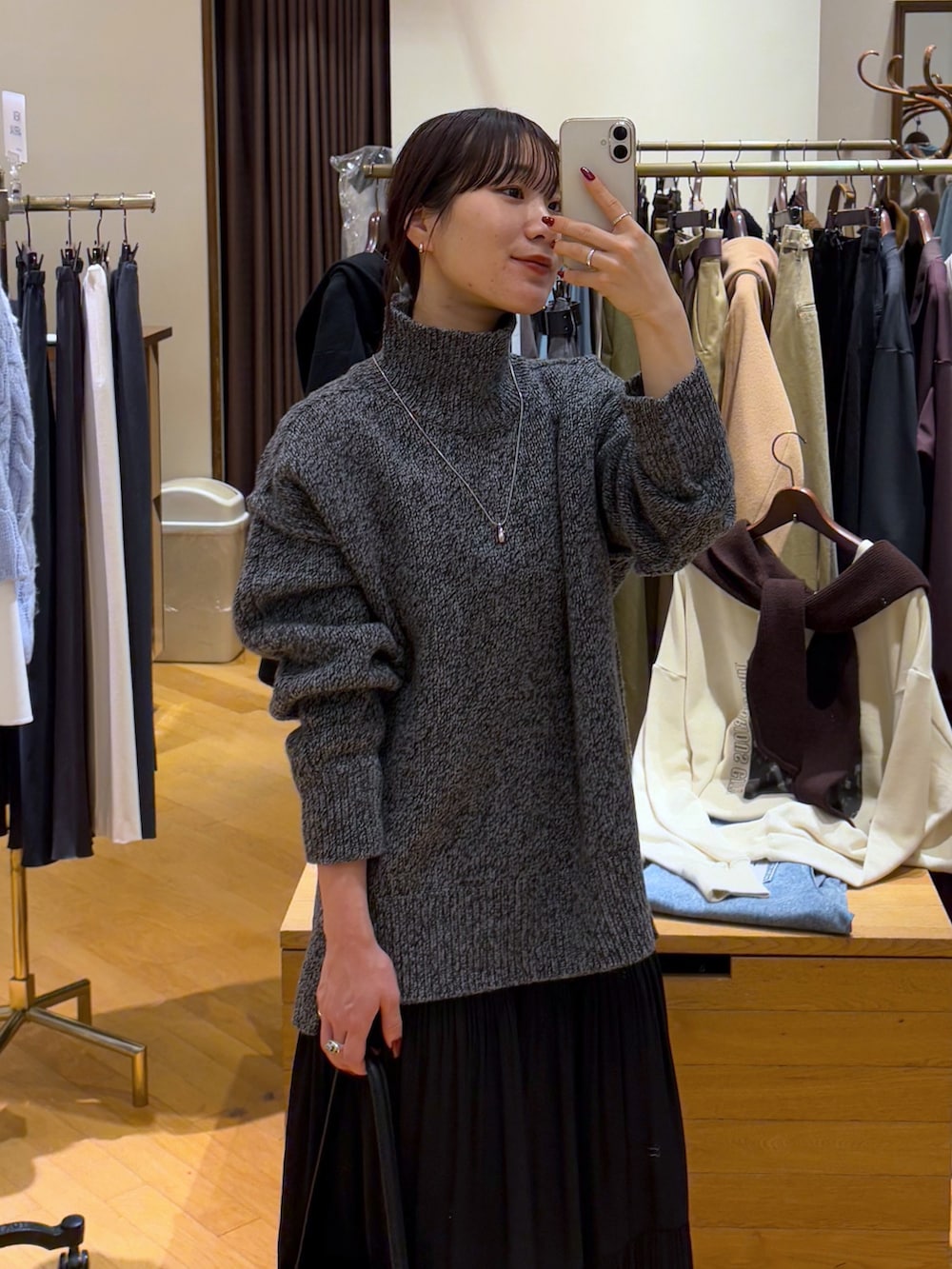 グレー系のニット/セーター、ブラック系のスカート、ブラック系のブーツを着用したレディースの秋コーディネートの3枚目の写真