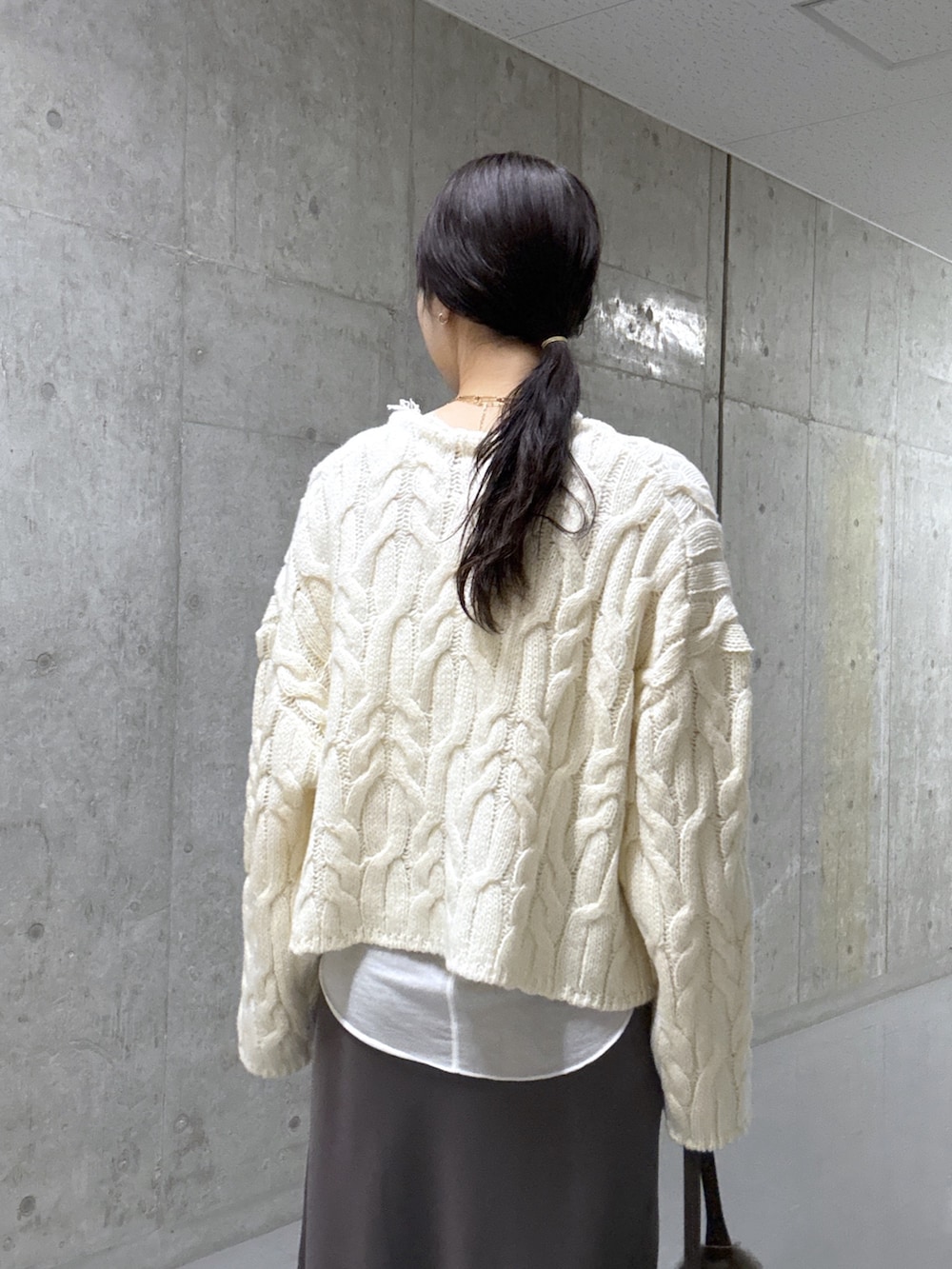 ホワイト系のTシャツ/カットソー、ホワイト系のニット/セーター、ブラウン系のスカートを着用したレディースの冬コーディネートの6枚目の写真