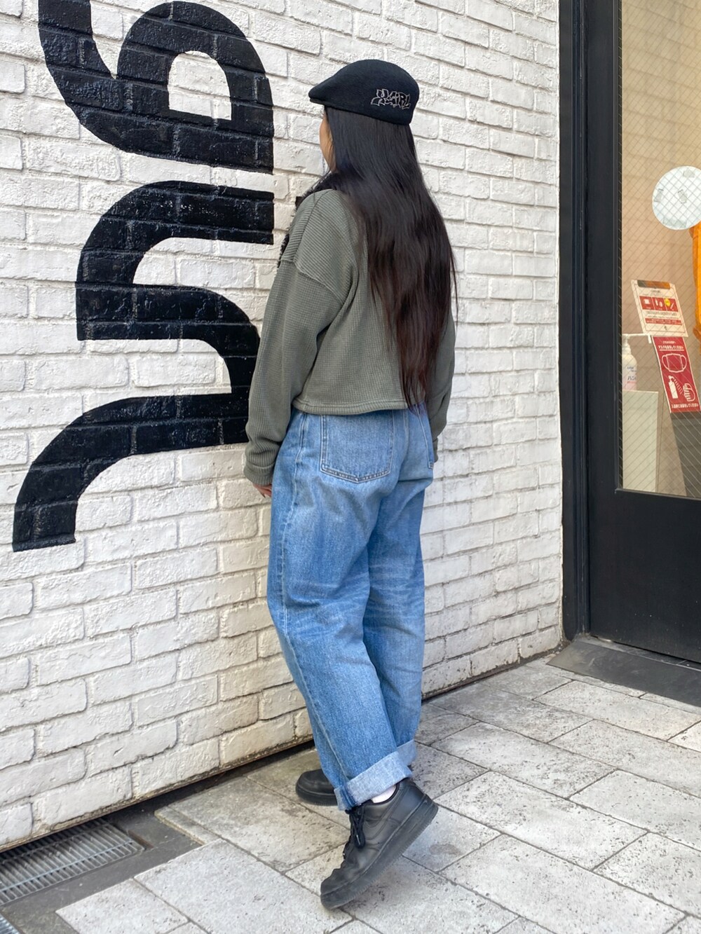 ブルー系のデニムパンツ、ブラック系のショルダーバッグ、グリーン系のTシャツ/カットソーを着用したレディースの秋コーディネートの2枚目の写真