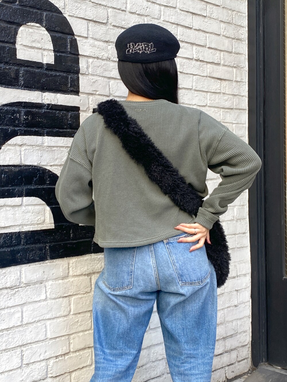 ブルー系のデニムパンツ、ブラック系のショルダーバッグ、グリーン系のTシャツ/カットソーを着用したレディースの秋コーディネートの3枚目の写真