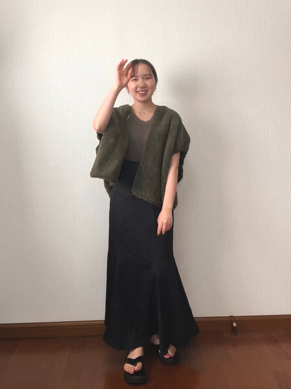 ブラック系のスカート、ブラック系のサンダル、グリーン系のタンクトップを着用したレディースの秋コーディネートの3枚目の写真