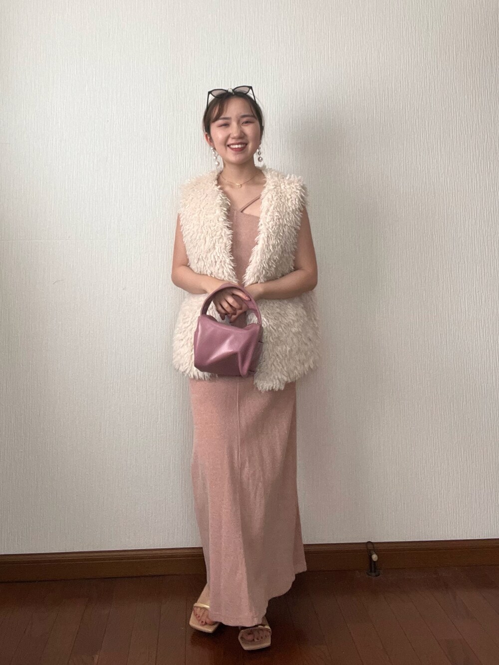 ホワイト系のベスト、オレンジ系のワンピース、ピンク系のボストンバッグを着用したレディースの秋コーディネートの3枚目の写真