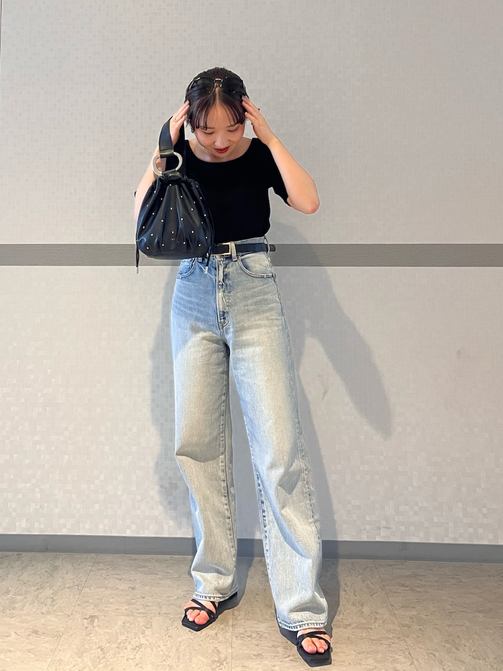 ブルー系のデニムパンツ、ホワイト系のTシャツ/カットソー、ブラック系のサンダルを着用したレディースの夏コーディネートの2枚目の写真