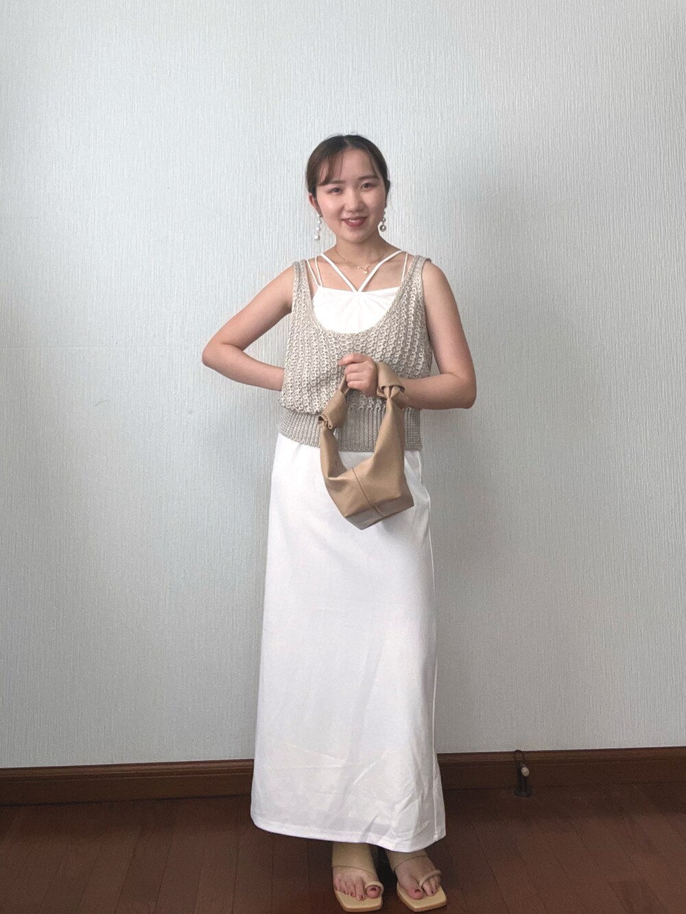 ホワイト系のベスト、ホワイト系のワンピース、ベージュ系のハンドバッグを着用したレディースの秋コーディネートの2枚目の写真