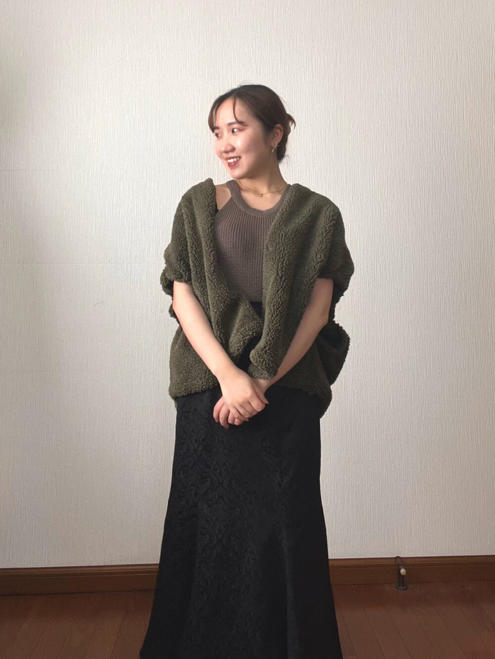 ブラック系のスカート、ブラック系のサンダル、グリーン系のタンクトップを着用したレディースの秋コーディネートの4枚目の写真