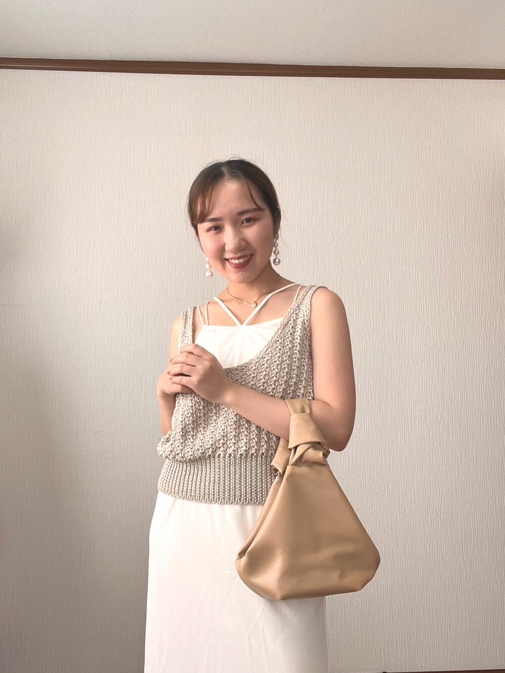 ホワイト系のベスト、ホワイト系のワンピース、ベージュ系のハンドバッグを着用したレディースの秋コーディネートの4枚目の写真