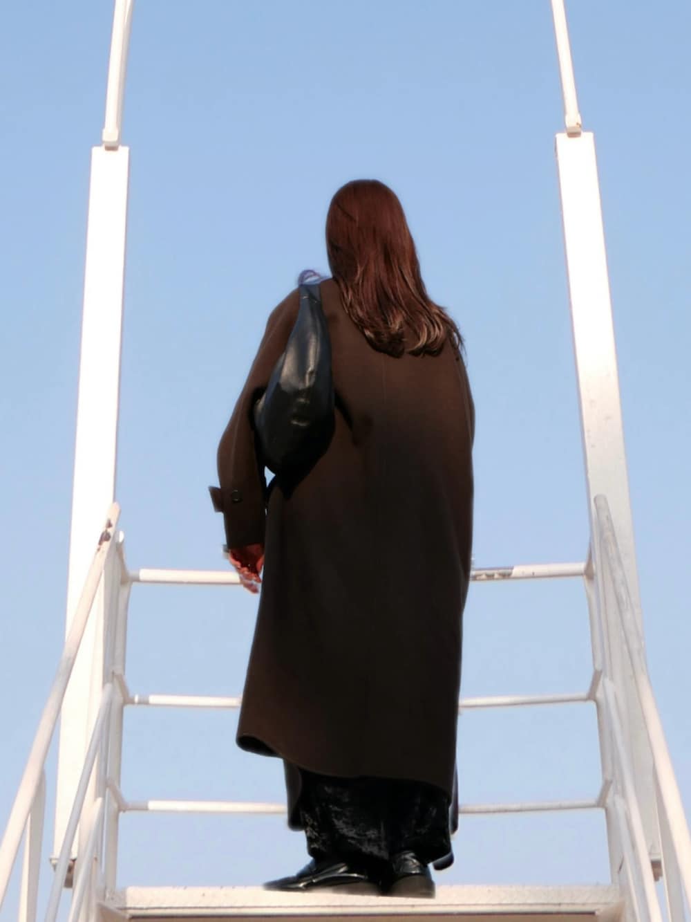 ホワイト系のカーディガン/ボレロ、ブラック系のスカートを着用したレディースの冬コーディネートの3枚目の写真