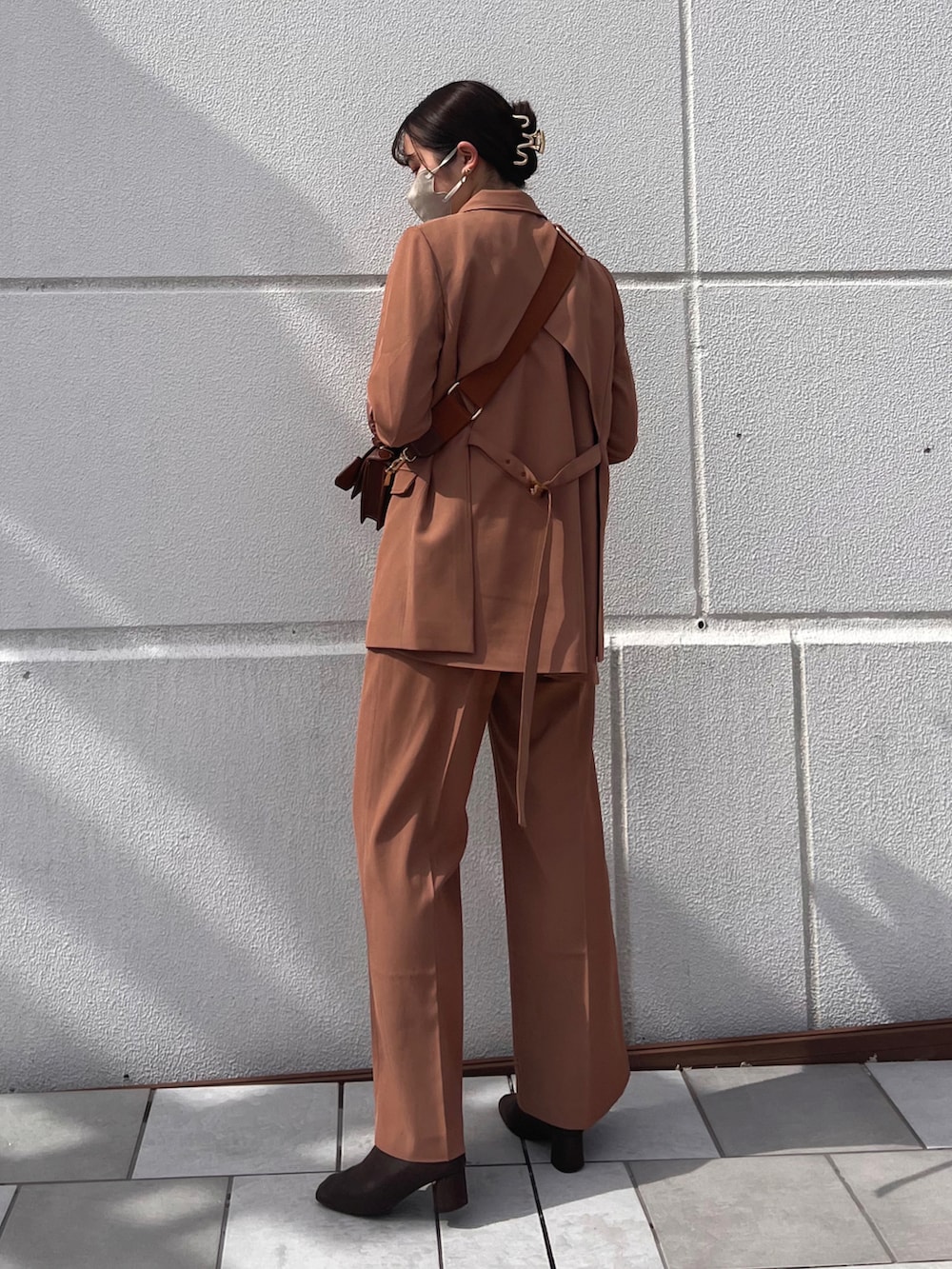 ブラウン系のテーラードジャケット、ブラウン系のブーツ、ブラック系のショルダーバッグを着用したレディースの秋コーディネートの2枚目の写真