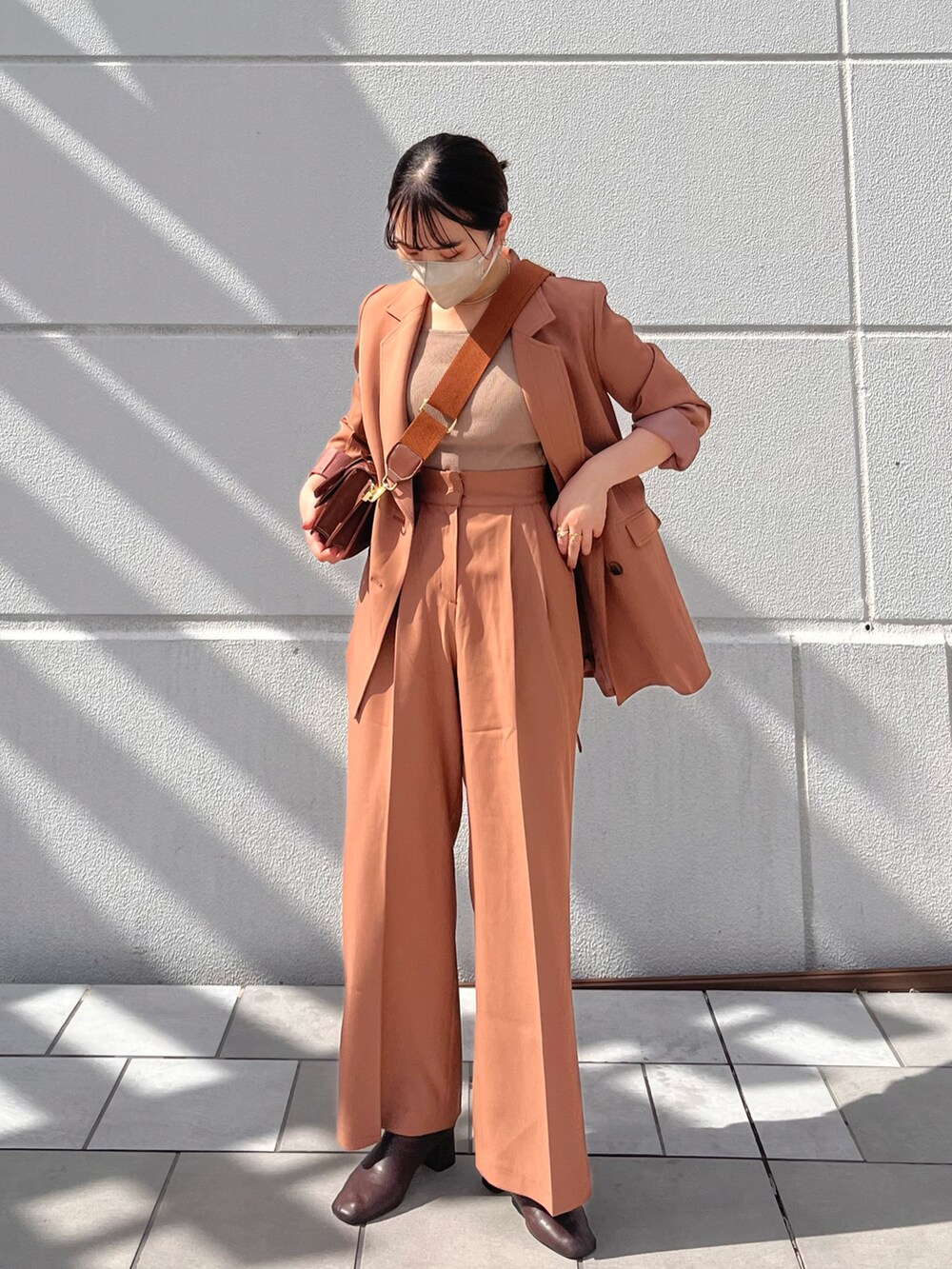 ブラウン系のテーラードジャケット、ブラウン系のブーツ、ブラック系のショルダーバッグを着用したレディースの秋コーディネートの4枚目の写真