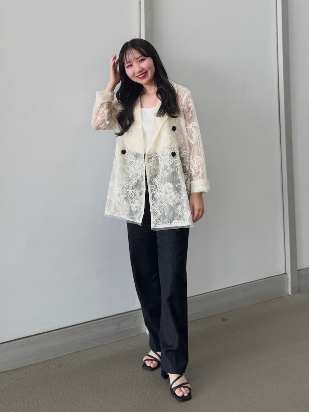 ホワイト系のテーラードジャケット、ホワイト系のキャミソール、ブラック系のパンツを着用したレディースの夏コーディネートの2枚目の写真
