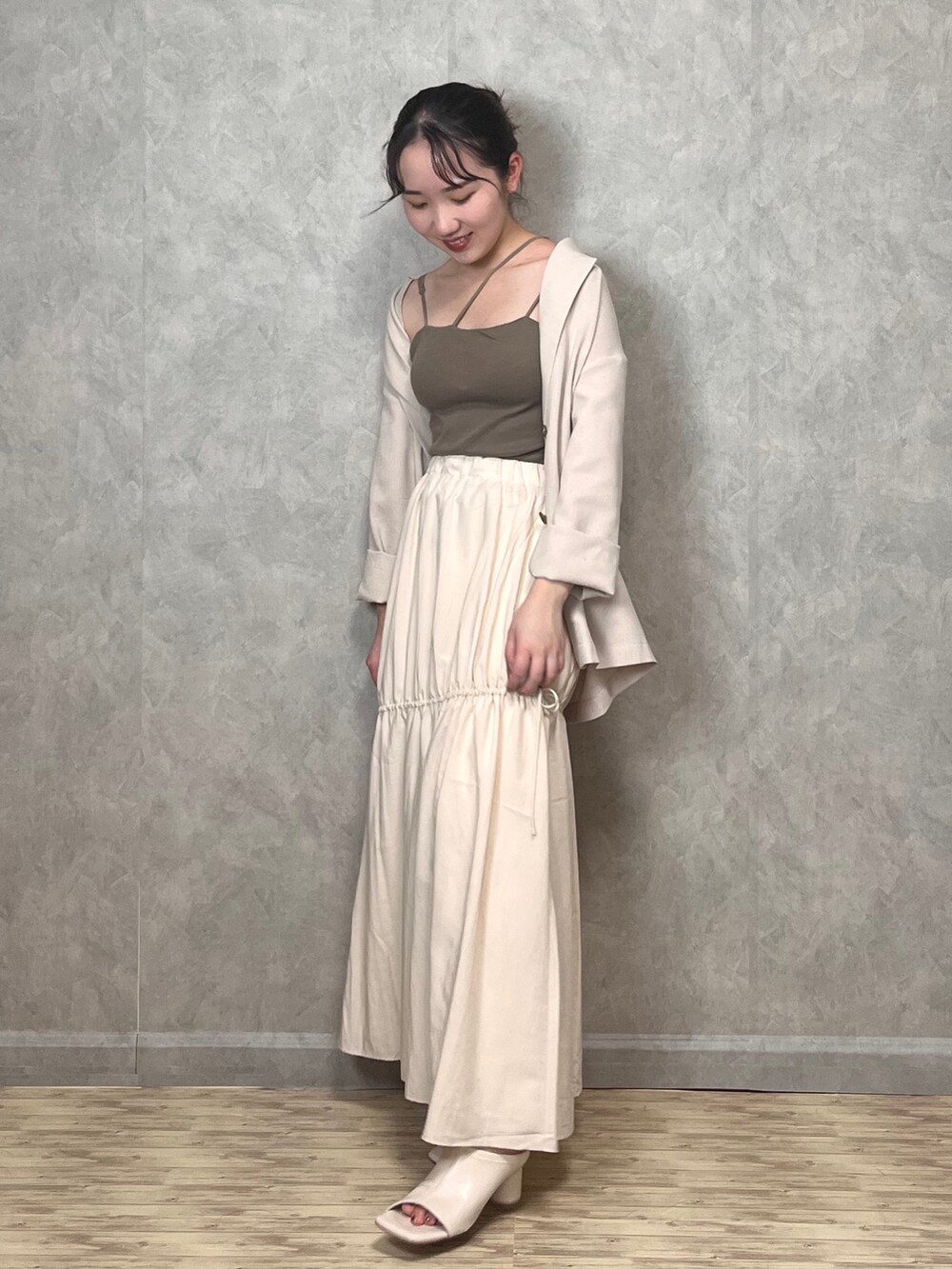 ホワイト系のスカート、ブラウン系のキャミソール、ホワイト系のテーラードジャケットを着用したレディースの秋コーディネートの2枚目の写真