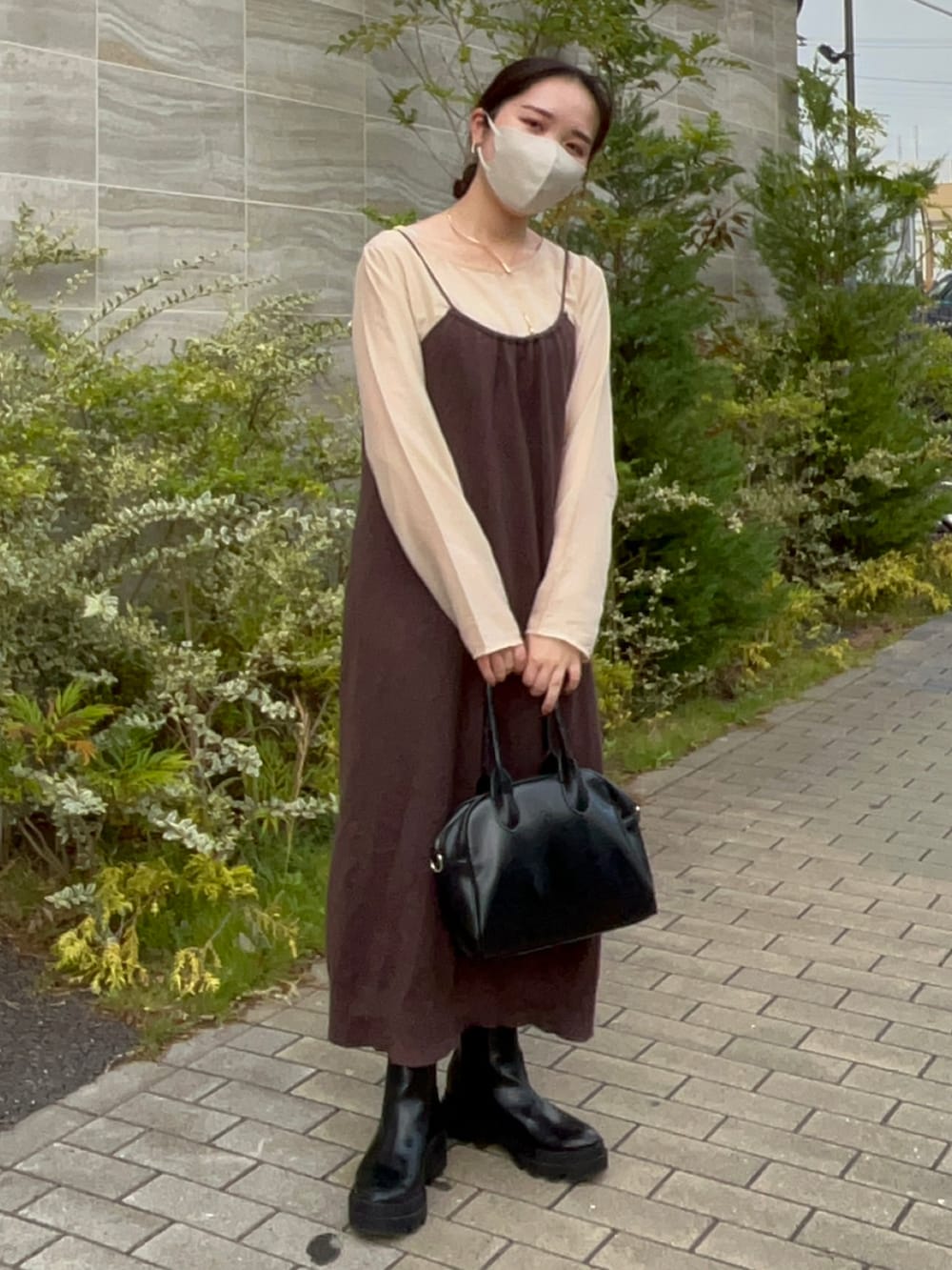 ブラック系のボストンバッグ、ブラウン系のワンピース、ベージュ系のTシャツ/カットソーを着用したレディースの秋コーディネートの2枚目の写真