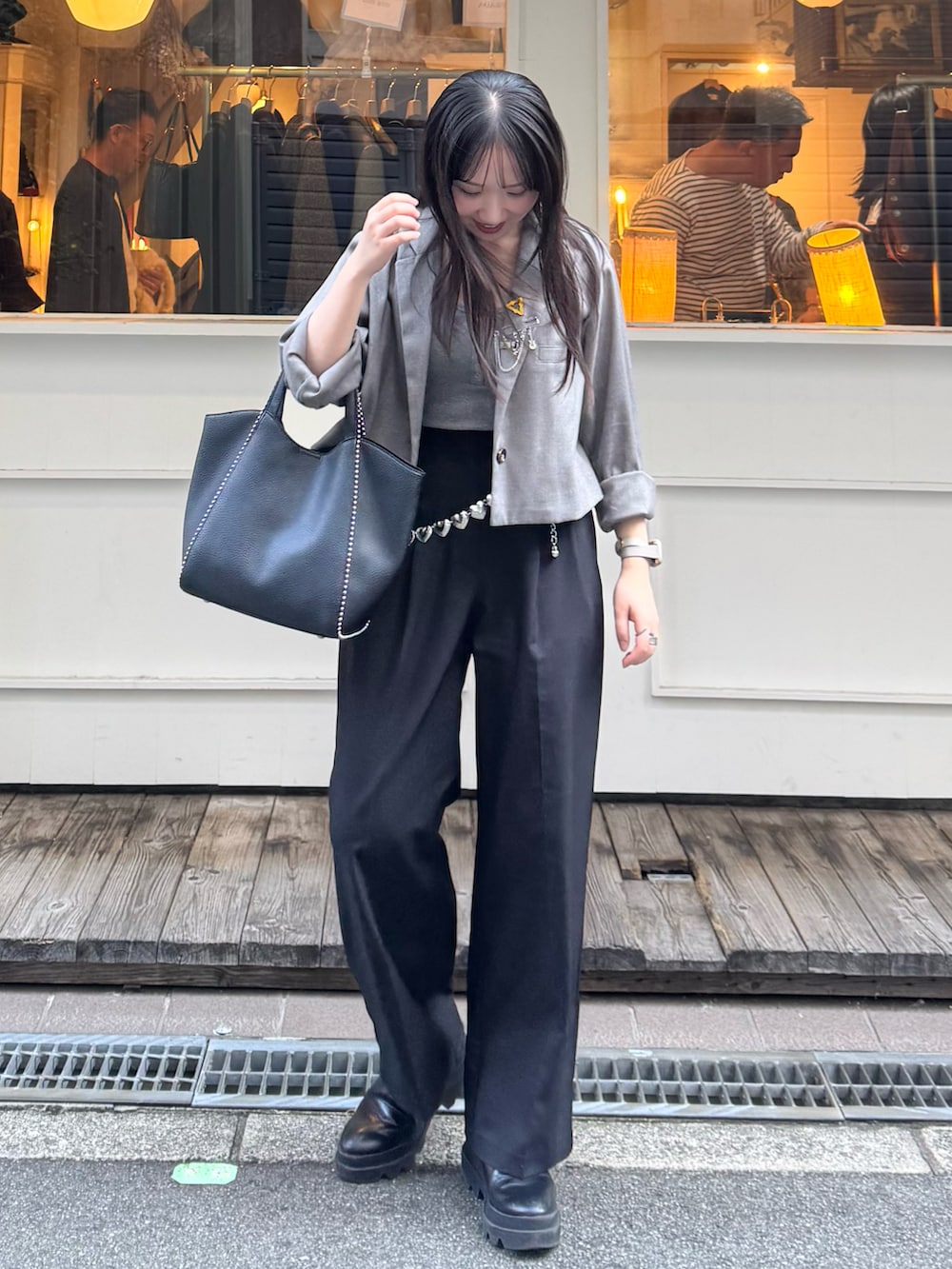 ブラック系のスラックス、ブラック系のブーツ、ブラック系のショルダーバッグを着用したレディースの秋コーディネートの2枚目の写真