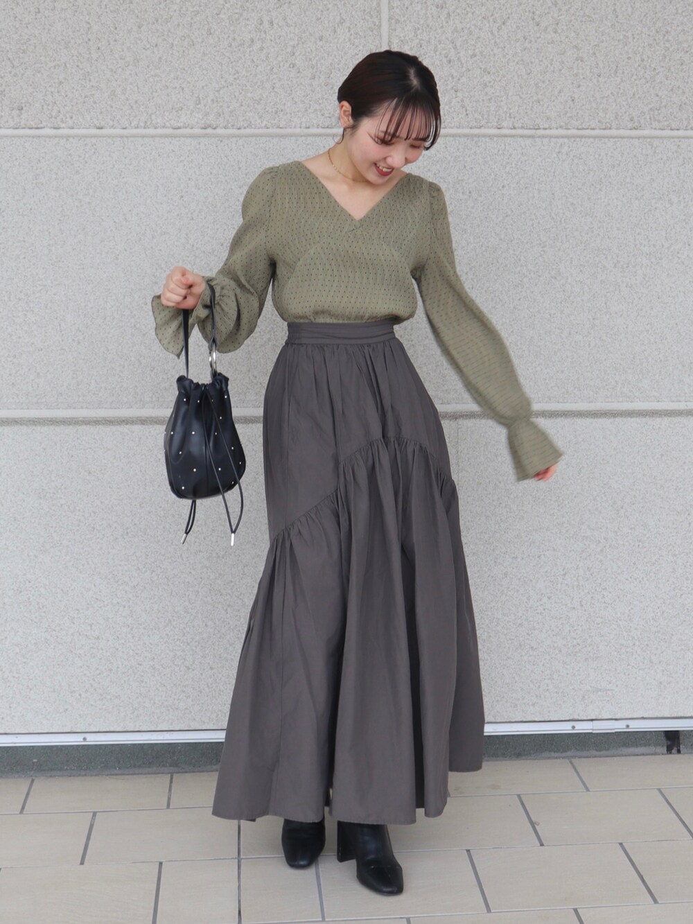 ホワイト系のベスト、グリーン系のシャツ/ブラウス、グレー系のスカートを着用したレディースの秋コーディネートの3枚目の写真