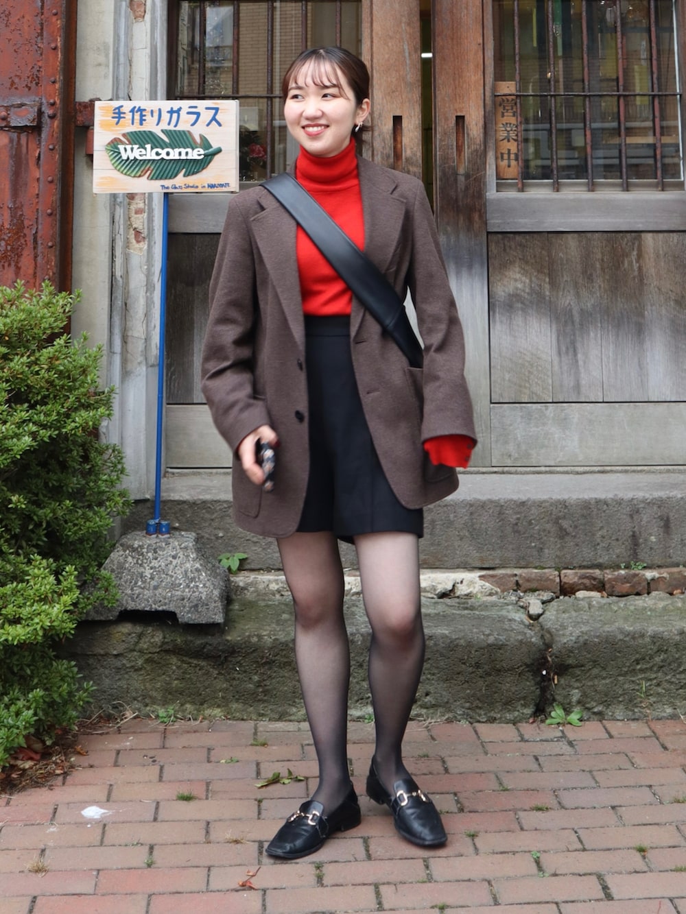 ブラック系のローファー、レッド系のニット/セーター、ブラウン系のテーラードジャケットを着用したレディースの秋コーディネートの2枚目の写真