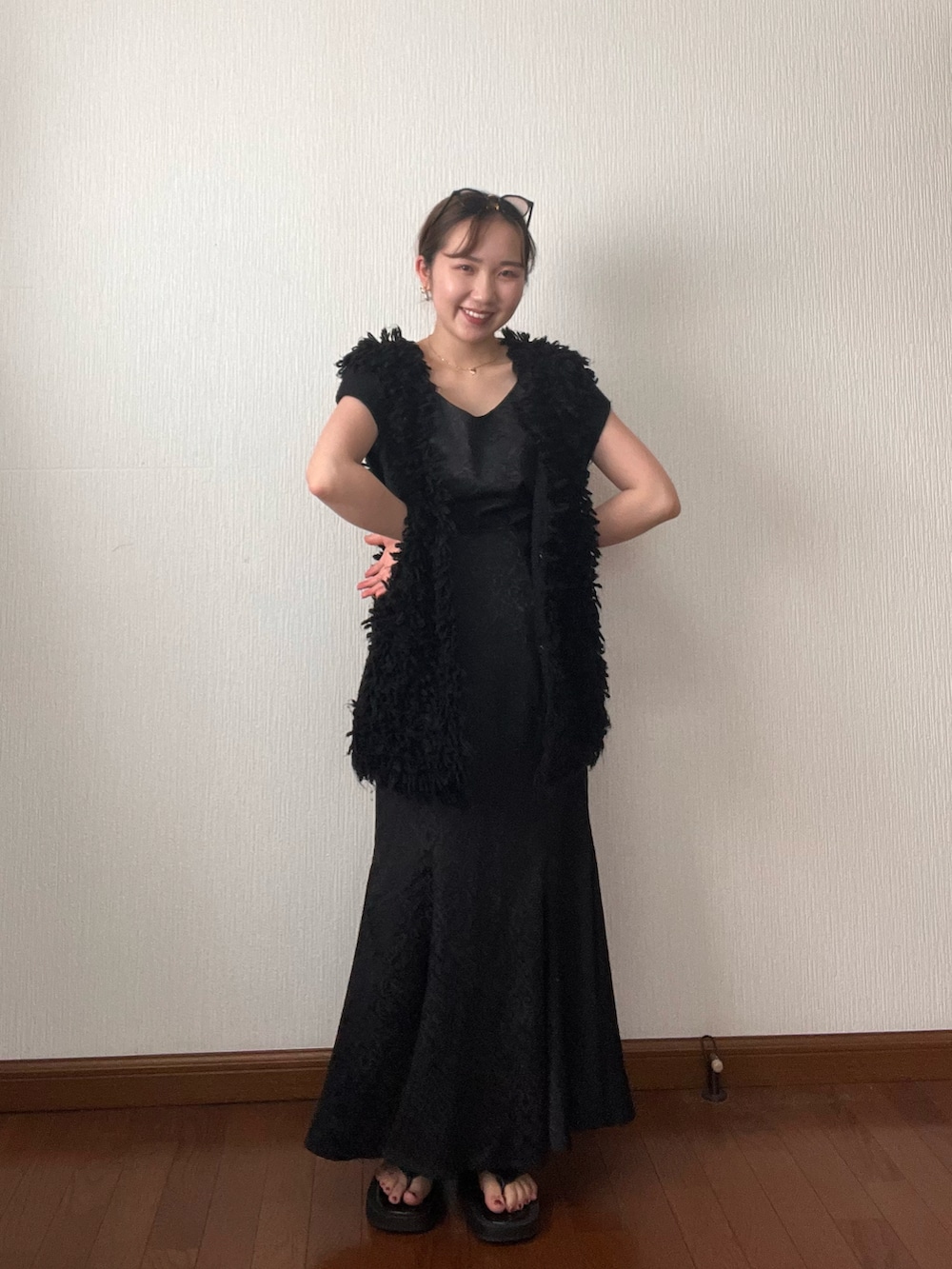 ブラック系のベスト、ブラック系のスカート、ブラック系のサンダルを着用したレディースの秋コーディネートの3枚目の写真