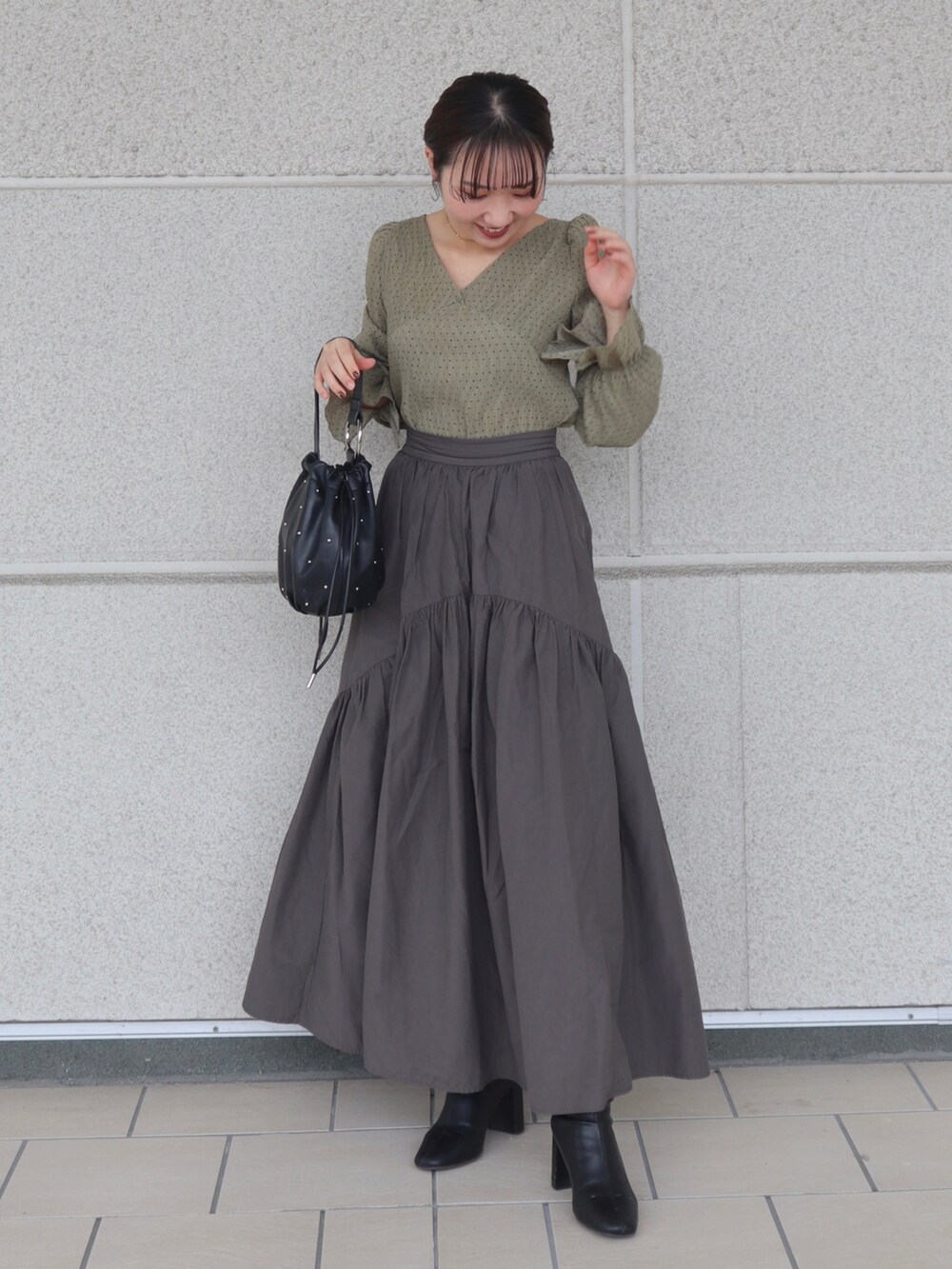 ホワイト系のベスト、グリーン系のシャツ/ブラウス、グレー系のスカートを着用したレディースの秋コーディネートの2枚目の写真