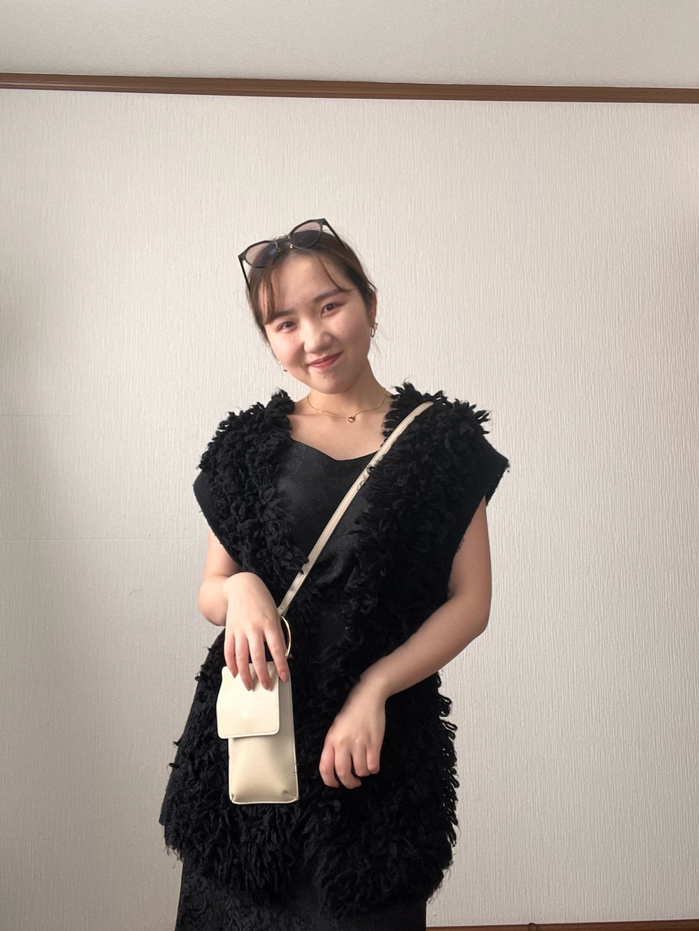 ブラック系のベスト、ブラック系のスカート、ブラック系のサンダルを着用したレディースの秋コーディネートの5枚目の写真