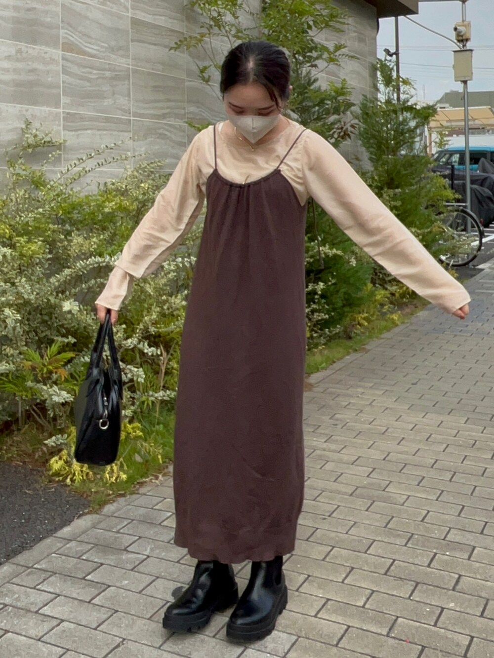 ブラック系のボストンバッグ、ブラウン系のワンピース、ベージュ系のTシャツ/カットソーを着用したレディースの秋コーディネートの3枚目の写真