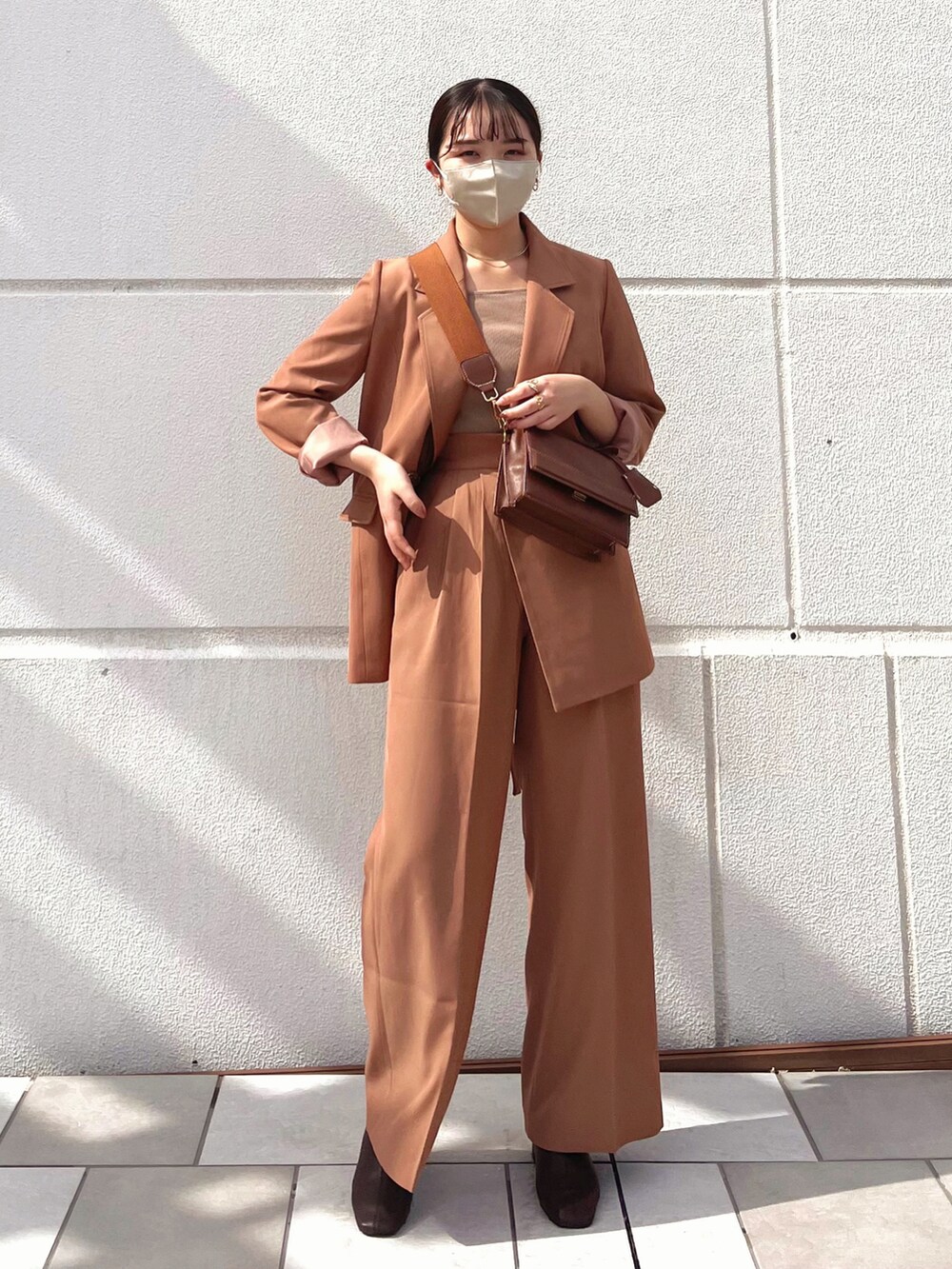 ブラウン系のテーラードジャケット、ブラウン系のブーツ、ブラック系のショルダーバッグを着用したレディースの秋コーディネートの5枚目の写真