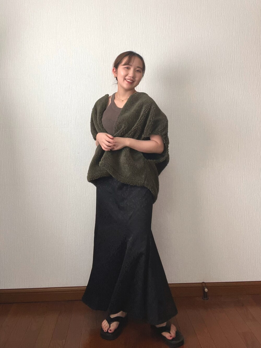 ブラック系のスカート、ブラック系のサンダル、グリーン系のタンクトップを着用したレディースの秋コーディネートの2枚目の写真