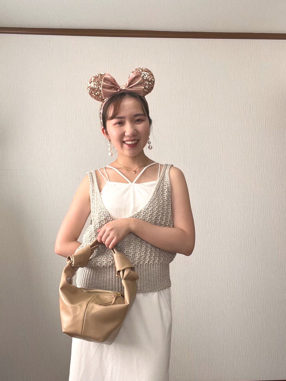 ホワイト系のベスト、ホワイト系のワンピース、ベージュ系のハンドバッグを着用したレディースの秋コーディネートの5枚目の写真