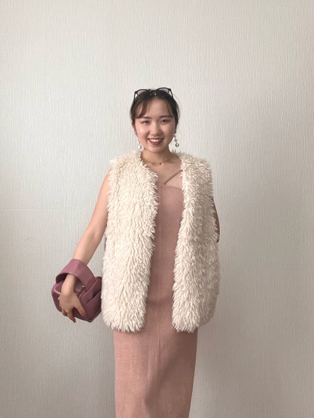 ホワイト系のベスト、オレンジ系のワンピース、ピンク系のボストンバッグを着用したレディースの秋コーディネートの5枚目の写真