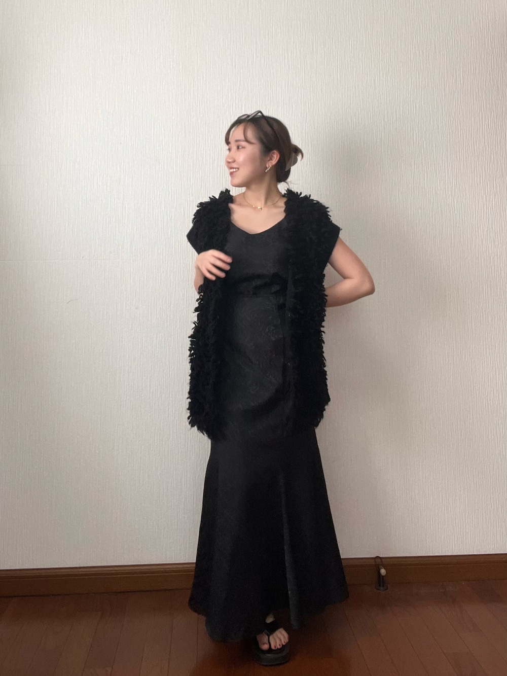 ブラック系のベスト、ブラック系のスカート、ブラック系のサンダルを着用したレディースの秋コーディネートの2枚目の写真