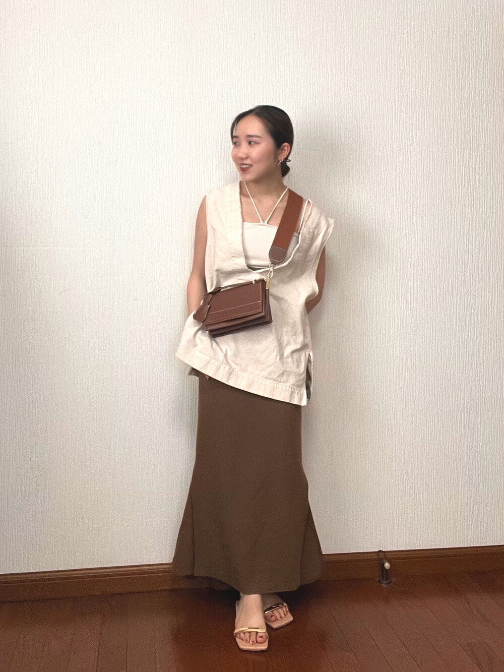 ブラウン系のショルダーバッグ、ホワイト系のベスト、ホワイト系のキャミソールを着用したレディースの秋コーディネートの3枚目の写真