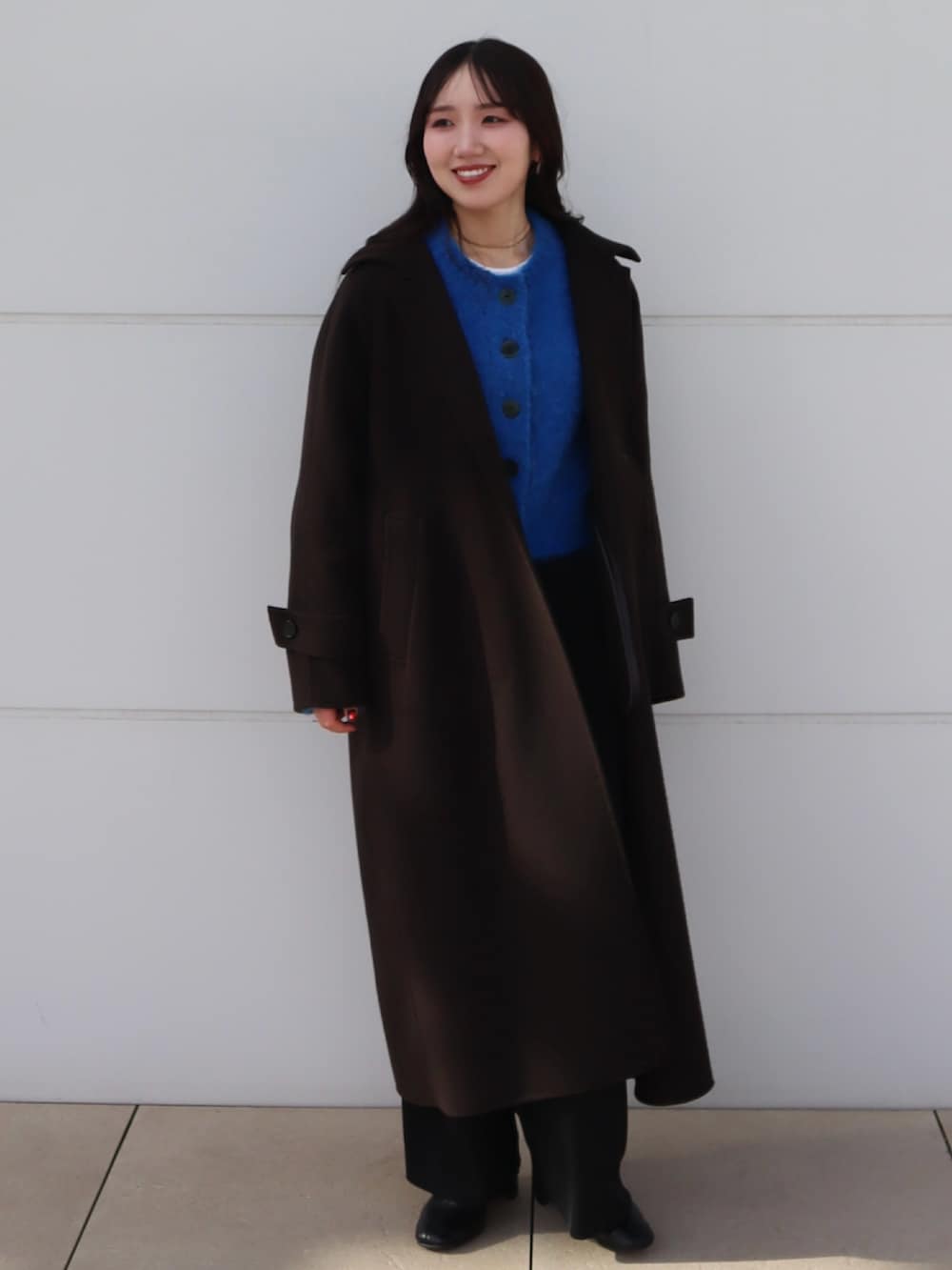 ブラック系のブーツ、ブルー系のカーディガン/ボレロ、ブラウン系のステンカラーコートを着用したレディースの秋コーディネートの2枚目の写真