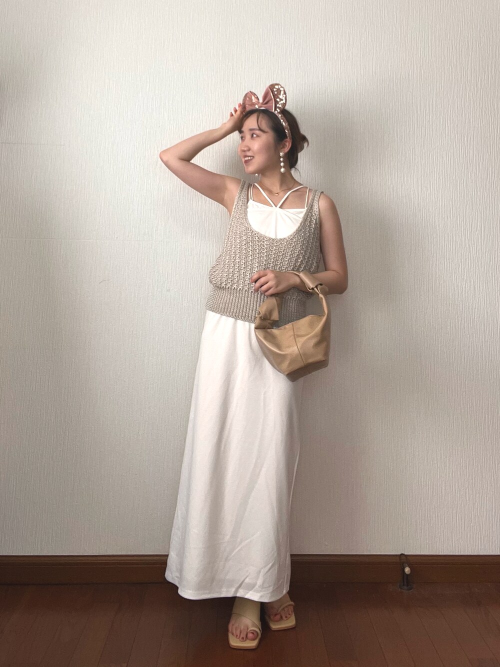 ホワイト系のベスト、ホワイト系のワンピース、ベージュ系のハンドバッグを着用したレディースの秋コーディネートの3枚目の写真