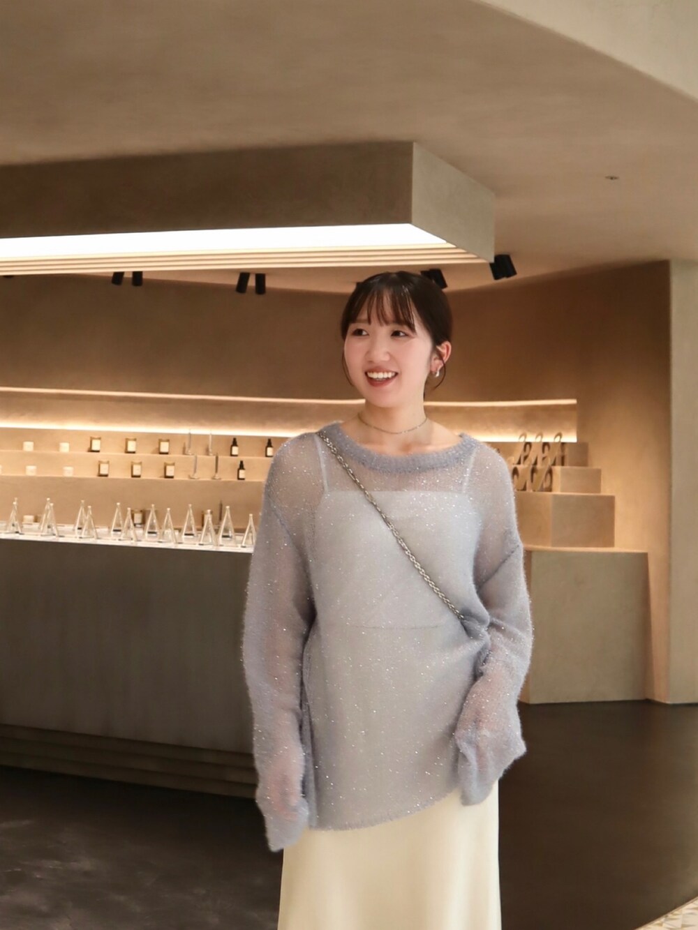 ホワイト系のスカート、ブルー系のニット/セーター、ブラック系のサンダルを着用したレディースの秋コーディネートの2枚目の写真