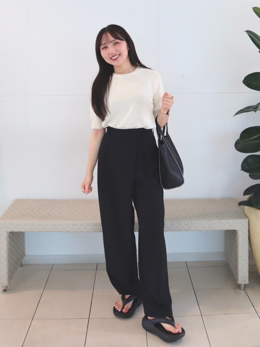 ホワイト系のニット/セーター、ブラック系のスラックス、ブラック系のショルダーバッグを着用したレディースの夏コーディネートの3枚目の写真
