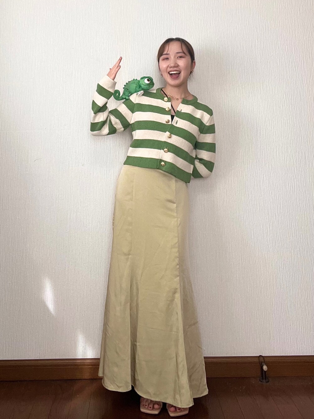 イエロー系のスカート、グリーン系のカーディガン/ボレロ、ベージュ系のサンダルを着用したレディースの秋コーディネートの2枚目の写真