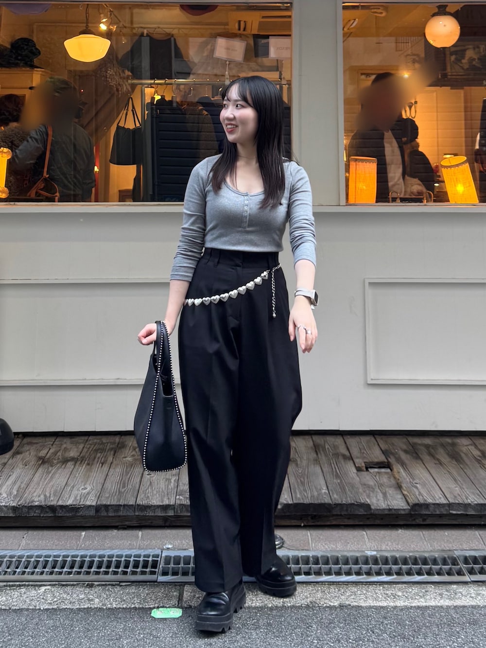 ブラック系のスラックス、ブラック系のブーツ、ブラック系のショルダーバッグを着用したレディースの秋コーディネートの4枚目の写真