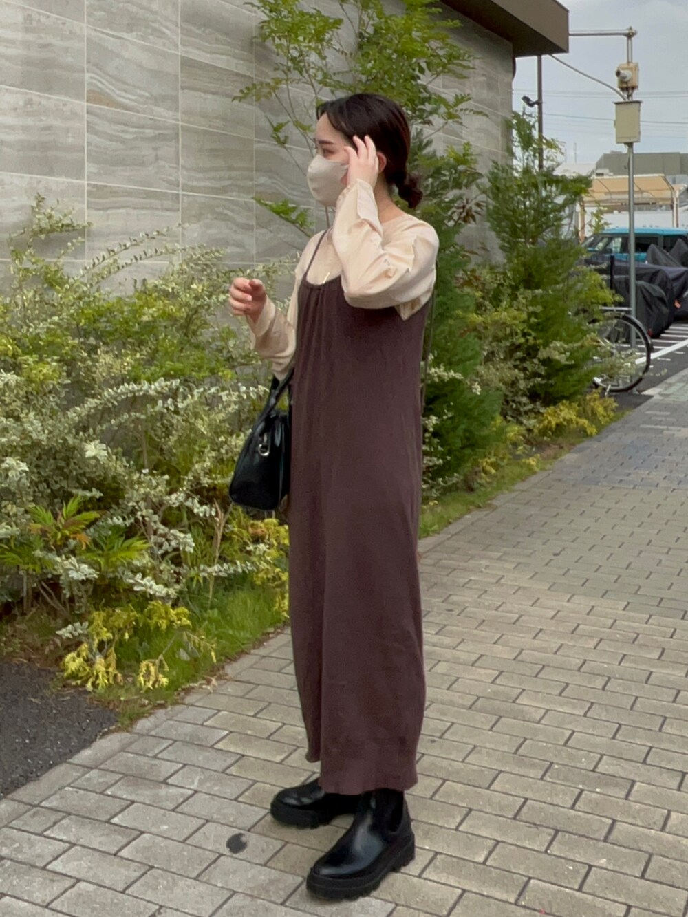 ブラック系のボストンバッグ、ブラウン系のワンピース、ベージュ系のTシャツ/カットソーを着用したレディースの秋コーディネートの4枚目の写真