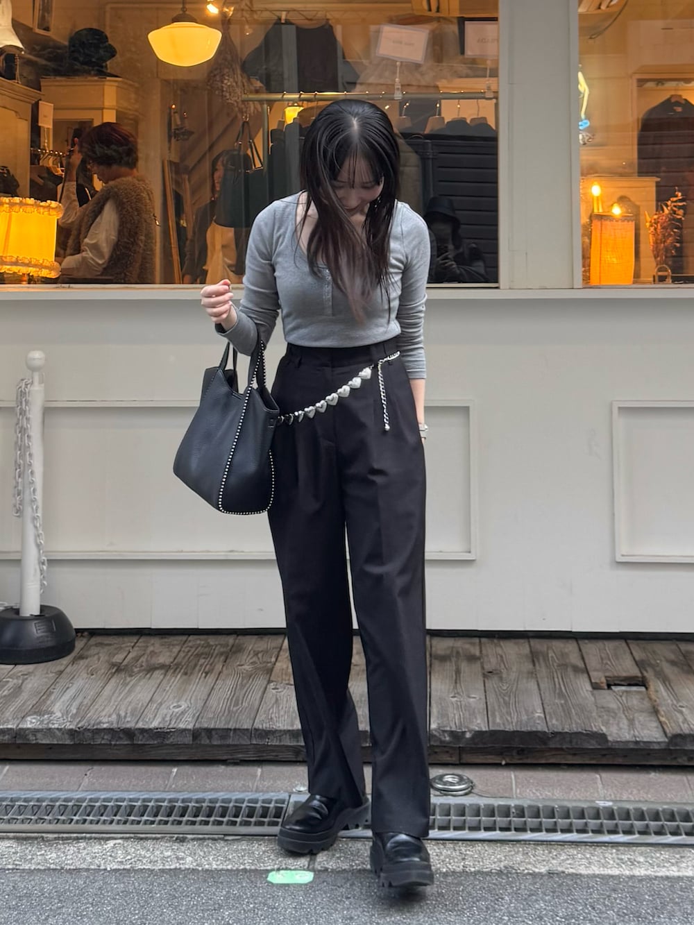 ブラック系のスラックス、ブラック系のブーツ、ブラック系のショルダーバッグを着用したレディースの秋コーディネートの3枚目の写真