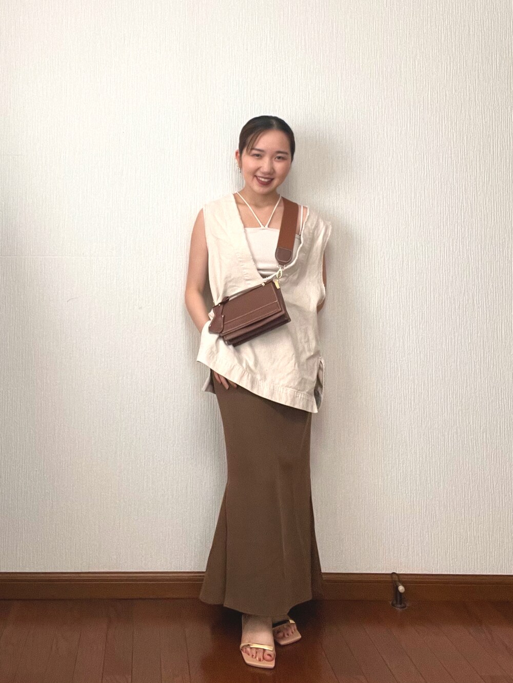 ブラウン系のショルダーバッグ、ホワイト系のベスト、ホワイト系のキャミソールを着用したレディースの秋コーディネートの2枚目の写真